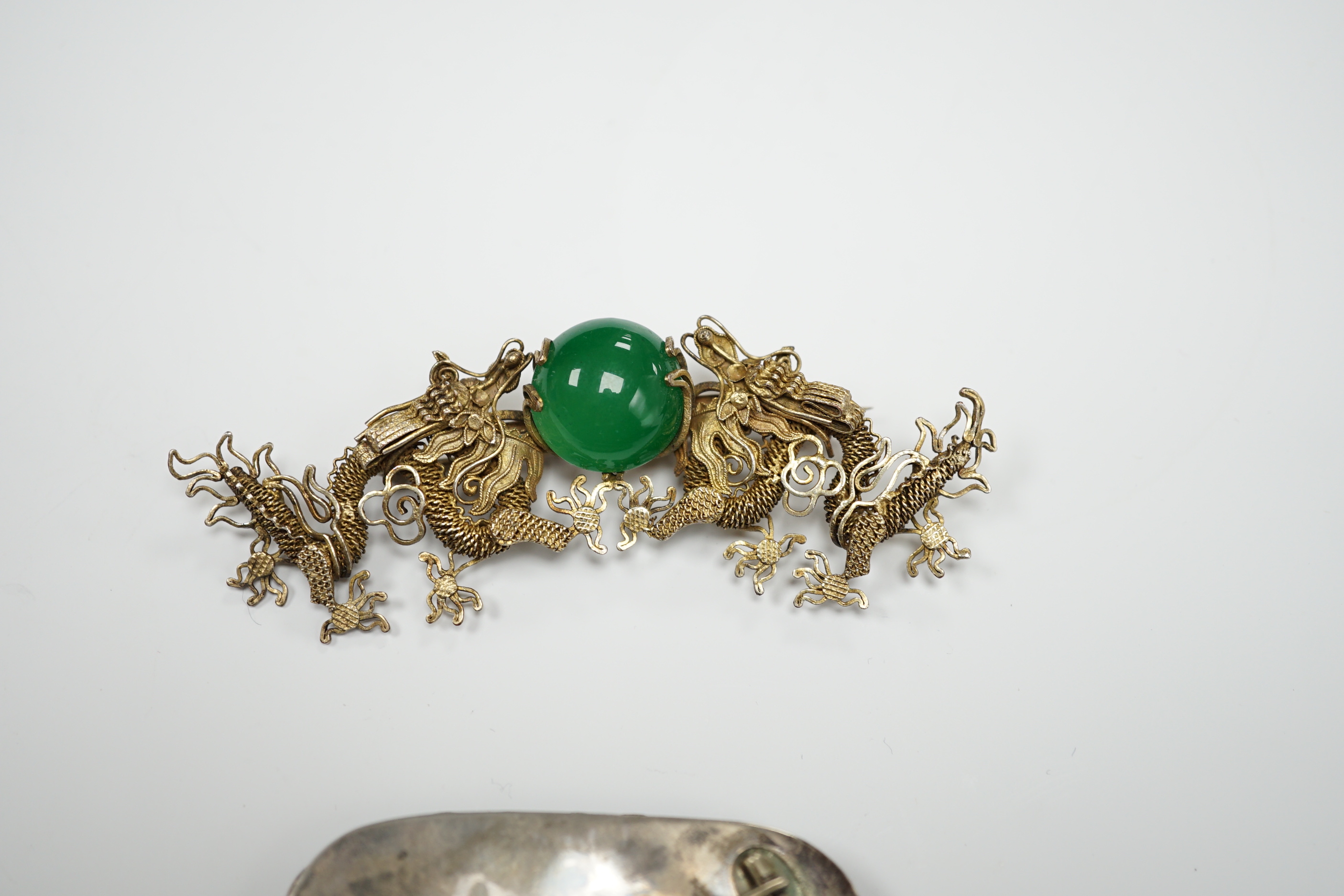 A Chinese? white metal and polychrome enamelled brooch, depicting a hare amongst foliage, 59mm(a.f.), together with a similar gilt white metal filigree and cabochon green paste set brooch.